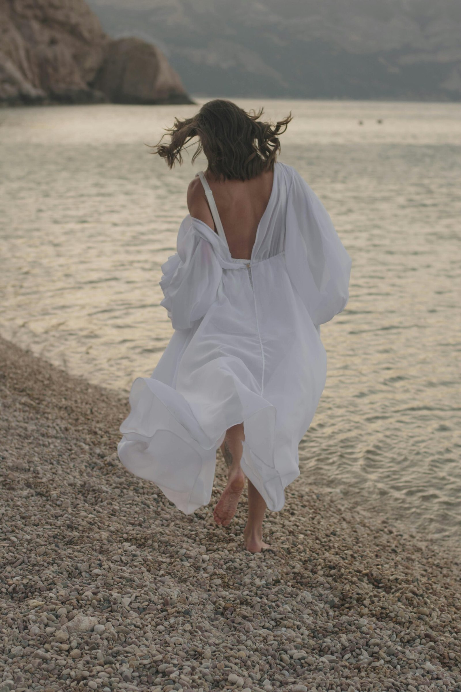 Femme libérée marchant au bord de l'eau, symbolisant le lâcher-prise, la libération des blocages émotionnels et l'apaisement intérieur.Épanouissement et sérénité retrouvée